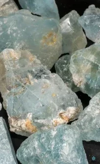 a cluster of pale blue topaz crystals with a cloudy, semi-transparent surface and mineral deposits