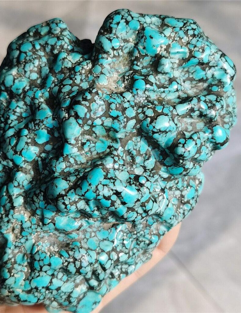 a rough spiderweb turquoise with a distinctive matrix of black veins across a bright blue surface